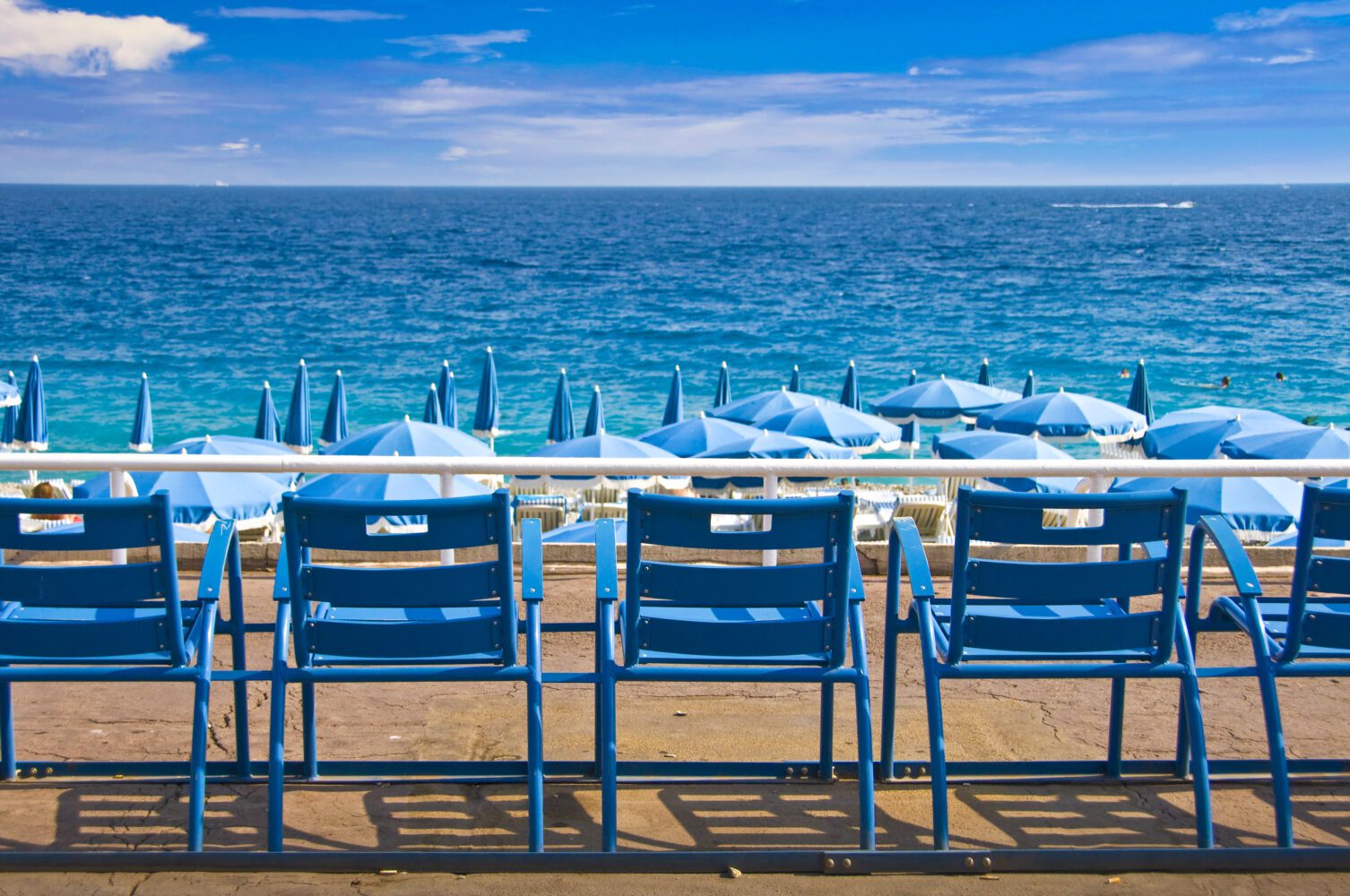 Blauwe strandstoelen op een zandstrand met uitzicht op zee.